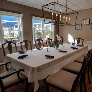 A beautifully set dining room with a modern chandelier and natural light streaming in through the windows.