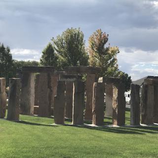 A stone monument surrounded by trees in a grassy area.