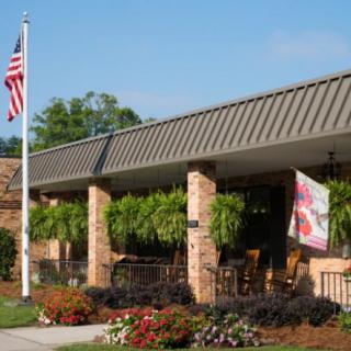 A building with brick columns, an American flag, and greenery in front.