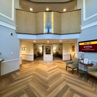 A modern hotel lobby with wooden flooring and seating areas.