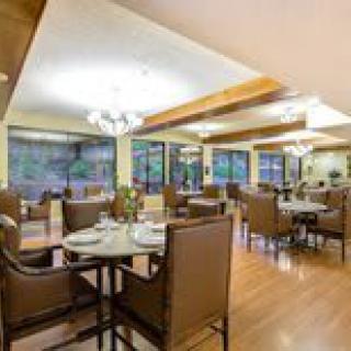 A well-appointed dining area with neatly arranged tables and chairs, featuring large windows and modern lighting fixtures.