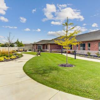 A modern building with a well-manicured lawn and winding pathway under a sunny sky.