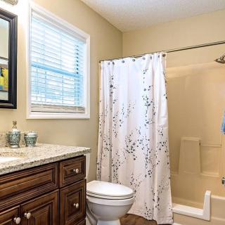 A cozy bathroom featuring a shower with a curtain, toilet, and vanity with a mirror.