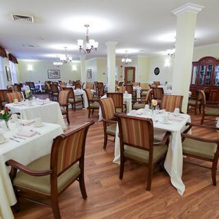 An elegant dining room setup with white tablecloths and wooden chairs.