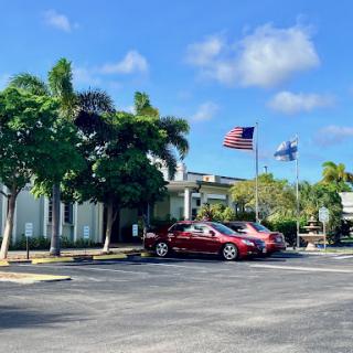 A sunny day at a commercial building with parked cars and waving flags.