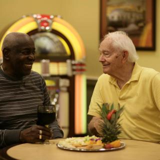 Two friends enjoying a conversation over drinks and snacks in a cozy setting.