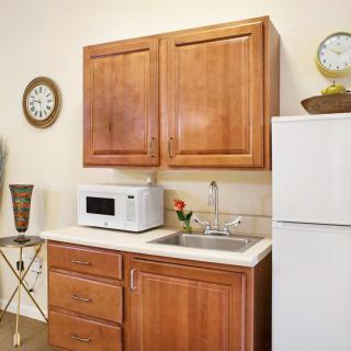 A cozy kitchen area featuring wooden cabinets, a microwave, a refrigerator, and a sink.