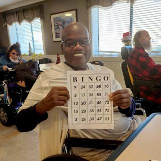 A joyful participant holding up a bingo card during a fun community game.