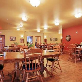 A cozy restaurant dining area with wooden tables and chairs, lit by warm lighting.