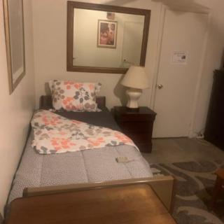 A cozy bedroom with a single bed, floral bedding, and a nightstand with a lamp.