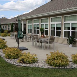 A suburban house with a well-maintained patio and outdoor seating area surrounded by landscaping.
