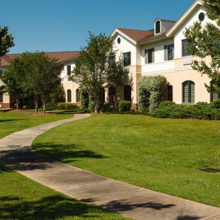 A scenic view of a building surrounded by lush greenery and a winding pathway.