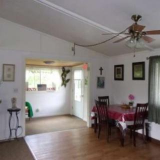 A cozy dining room with a table and chairs, featuring a ceiling fan and wood flooring.