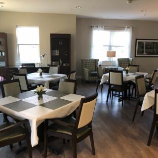 A cozy dining area with neatly arranged tables and chairs, featuring natural light from the windows.