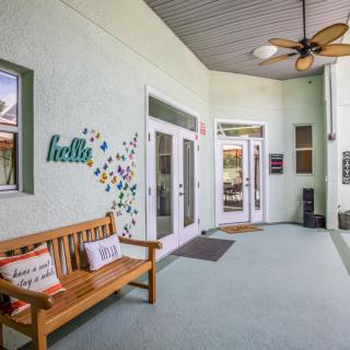 A welcoming entrance area featuring a wooden bench, decorative pillows, and a ceiling fan.