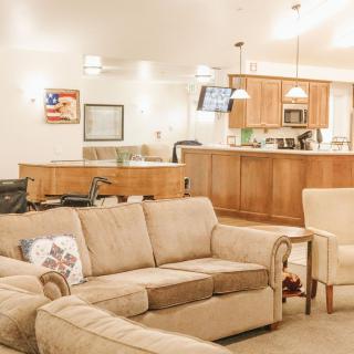 A cozy living room with an open kitchen layout, featuring a comfortable sofa and warm lighting.