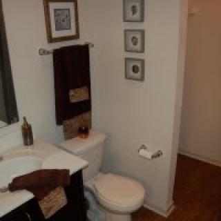 A neatly organized bathroom featuring a sink, toilet, and wall decor.