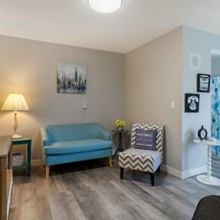 A cozy living room with modern decor, featuring a blue sofa, patterned armchair, and ambient lighting.