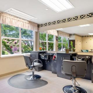 A well-lit salon interior with styling chairs and large windows.