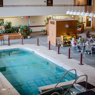 An indoor pool located in a hotel lobby with adjacent dining and seating areas.