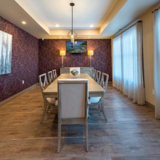 A modern dining room featuring a long table with chairs, elegant lighting, and wall art.