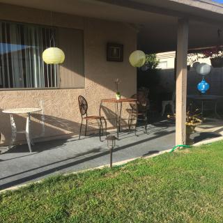 A sunny patio with outdoor seating, decorative lanterns, and a grassy yard.