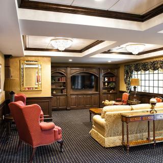 A classic-style living room featuring comfortable seating, elegant woodwork, and a large television.