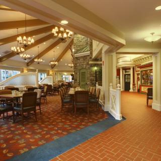A spacious and elegantly designed dining area with tables, chairs, and chandeliers.