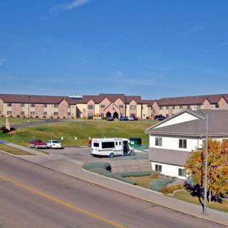 A suburban scene featuring residential buildings, a road, and parked vehicles on an autumn day.