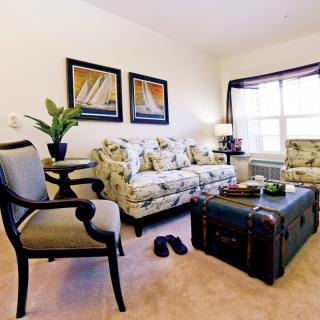 A cozy living room with floral sofas and nautical-themed artwork.