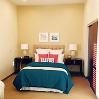 A neatly arranged bedroom featuring a double bed with teal bedding, flanked by matching nightstands and lamps.