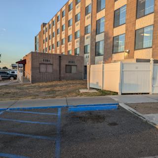An exterior view of a multi-story building with a parking lot in the foreground.
