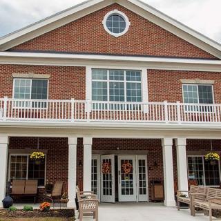 A two-story brick building with a porch and large windows.