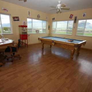A spacious game room featuring a pool table, desk, and large windows with scenic views.