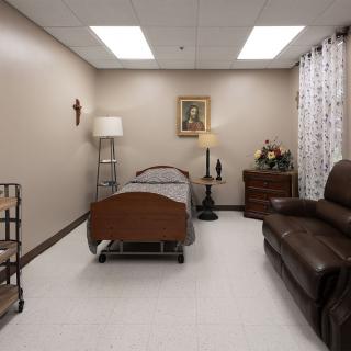 A hospital room featuring a bed, couch, lamp, and decorative elements.
