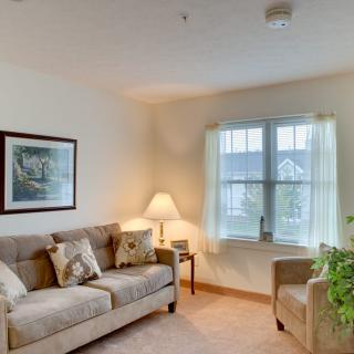 A cozy living room with a sofa, armchair, and soft lighting.