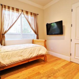 A cozy bedroom with a single bed, television, and hardwood floors.