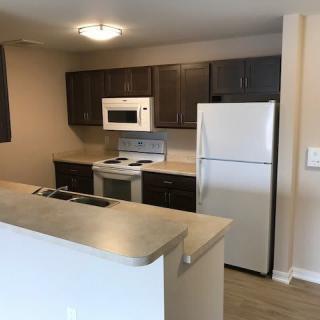 A modern apartment kitchen with appliances including a microwave, stove, and refrigerator.