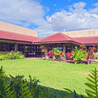 A picturesque building surrounded by vibrant flowers and lush green grass under a sunny sky.