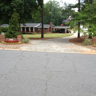 A suburban house with a driveway surrounded by trees and landscaping.