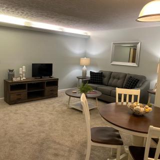 A cozy living room with a sofa, TV stand, dining set, and decorative elements.