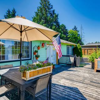 A sunny deck with outdoor furniture and an umbrella, featuring a garden and an American flag.