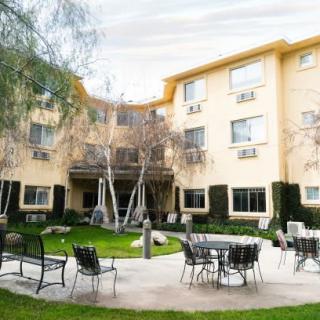 A view of a building with a courtyard featuring tables, chairs, and surrounding greenery.