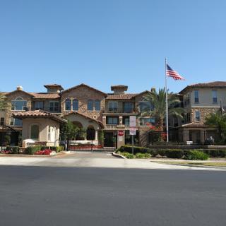 A charming residential building featuring classic architecture, complemented by a landscaped entrance and an American flag waving in the breeze.