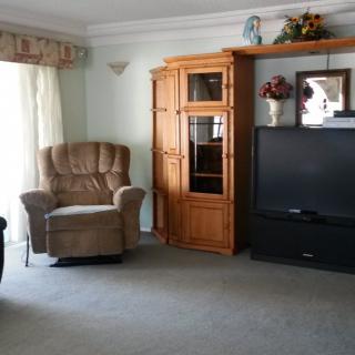 A cozy living room with an armchair, TV, and wooden cabinet.