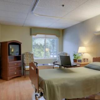 A hospital room with a bed, furniture, and a window.