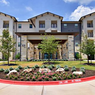 A modern residential building with landscaped gardens and a welcoming entrance.