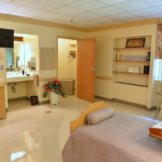 A well-equipped hospital patient room featuring a bed, furniture, and a clean bathroom area.