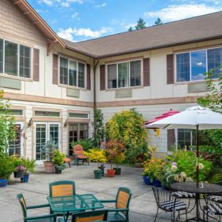 A sunny courtyard with outdoor seating and lush plants.
