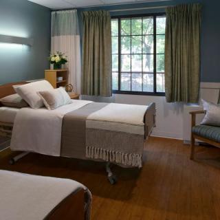 A well-lit hospital room with twin beds and a large window.